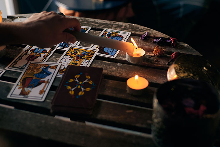 A tarot reader performing tarot card readings, spreading tarot cards on a table with a lit candle beside them.